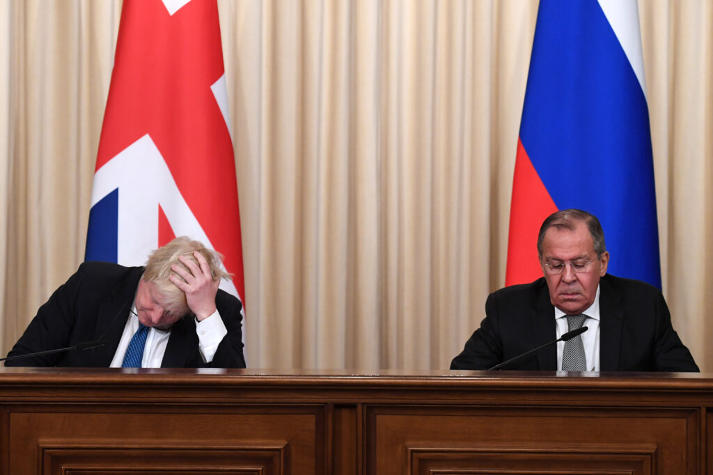Boris Johnson sits next to Sergei Lavrov at a press conference in Moscow. Behind them are the flags of the United Kingdom and Russia